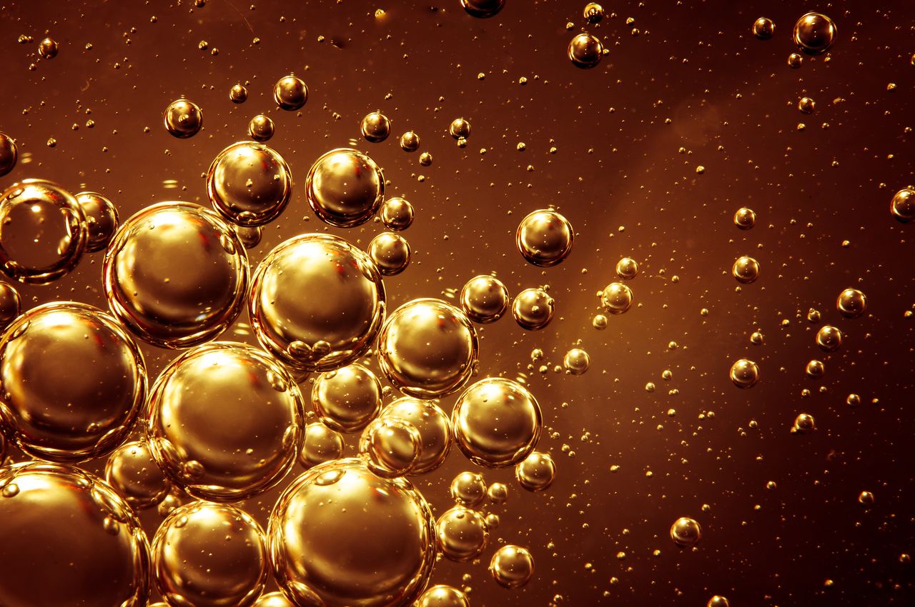 Abstract image of golden bubbles floating on a brown background, creating a mesmerizing effect.
